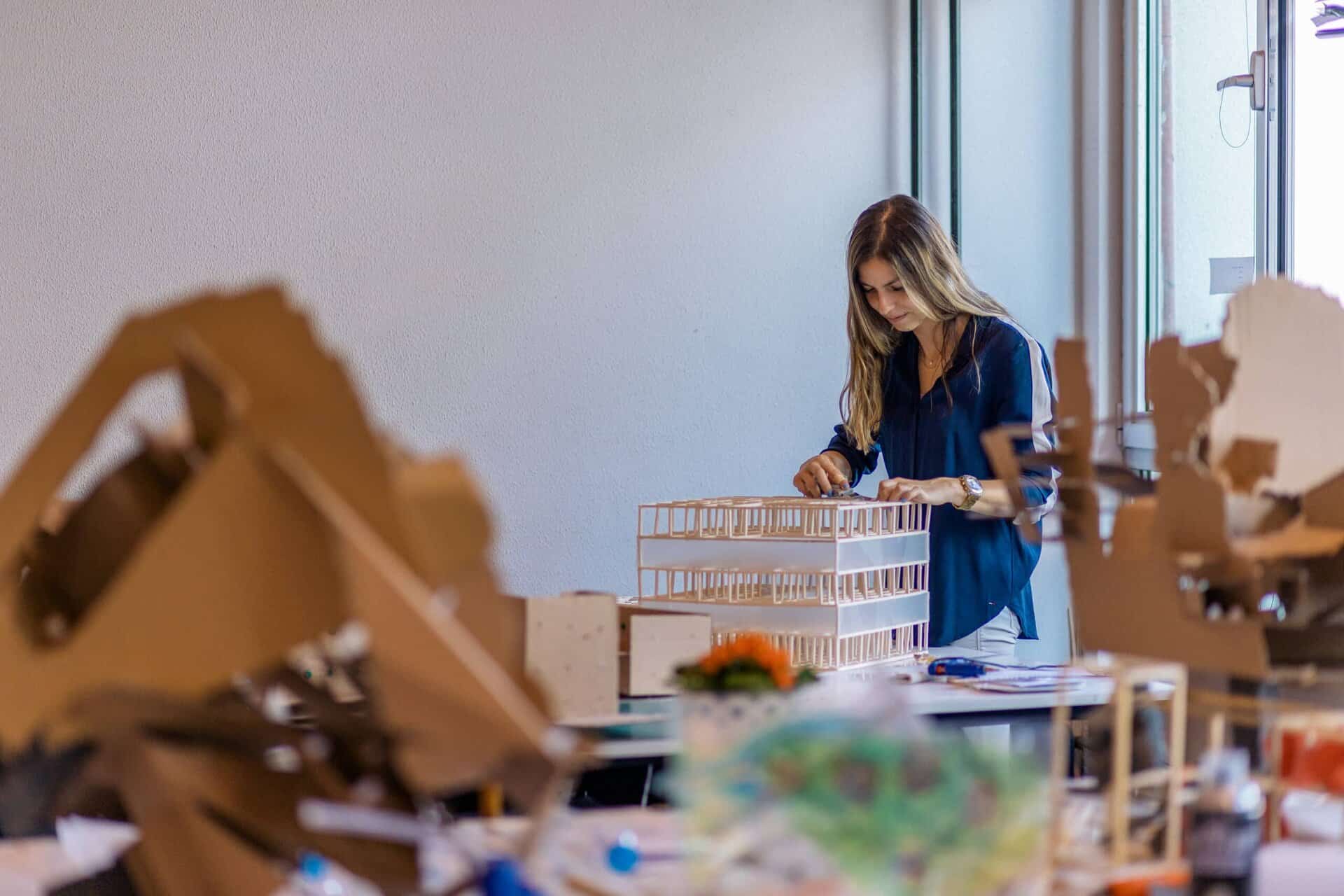 Student working on engineering and sustainability project with architectural models.