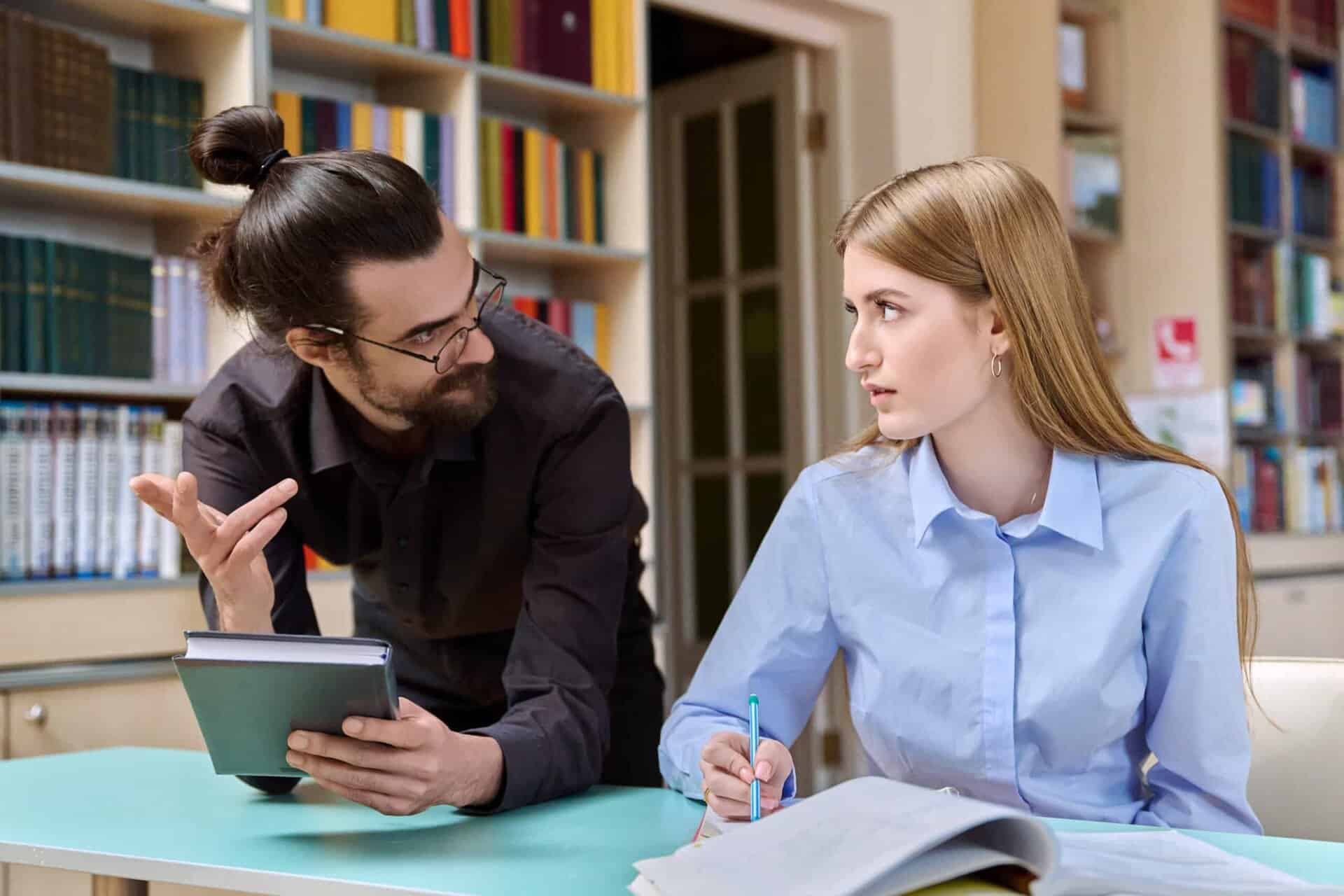 Two students engaged in a psychology and leadership discussion in a library setting.